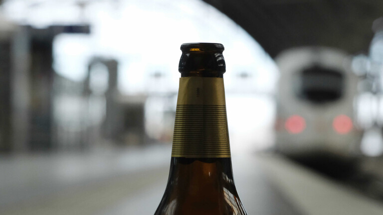 Eine leere Flasche Bier steht an einem Bahnsteig