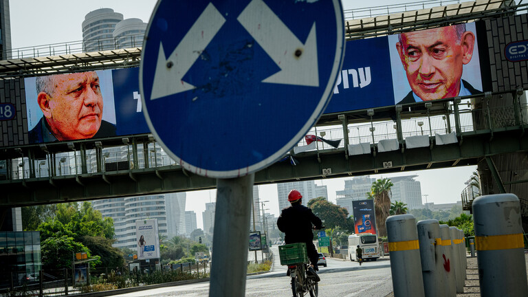 Ein Radfahrer fährt in Tel Aviv unter einer Fußgängerbrücke hindurch, an der elektronische Wahlplakate zu sehen sind, auf denen der ehemalige Stabschef der israelischen Streitkräfte, Gadi Eisenkot (links), und Ministerpräsident Benjamin Netanjahu (rechts) abgebildet sind. Am 27. Oktober finden in Israel Parlamentswahlen statt.
