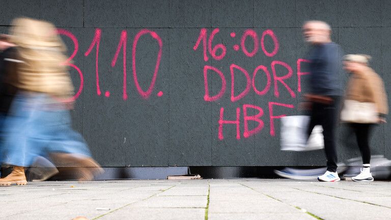 An einer Baustellen-Holzverkleidung auf der berühmten Düsseldorfer KÖ (Königsallee) ist mit rosaroter Farbe der Schriftzug „31.10. 16:00 DDORF HFB“ gesprayt.