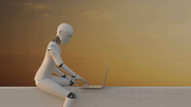 Ein Roboter sitzt vor einem Laptop und tippt auf der Tastatur