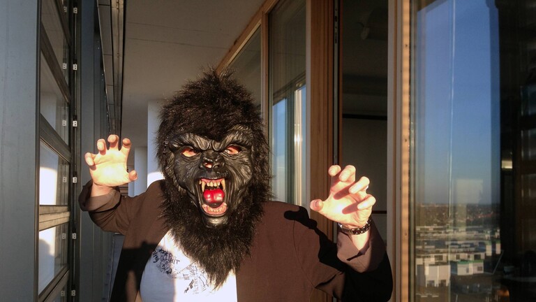 Frau mit Gorillamaske hält ihre Hände wie Klauen