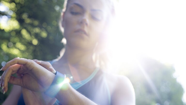 Eine junge Frau schaut auf ihren Fitnesstracker
