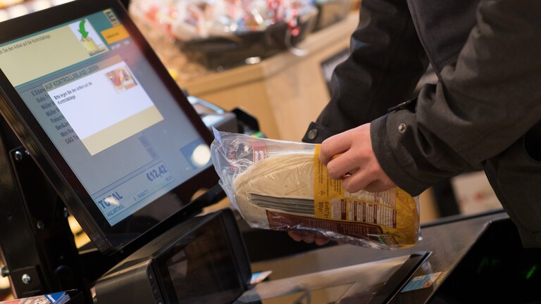 Ein Mann scannt Lebensmittel an einer SB-Kasse