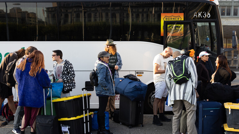 Besucher des Burning-Man-Festivals warten im August des Jahres 2024 auf den Bus