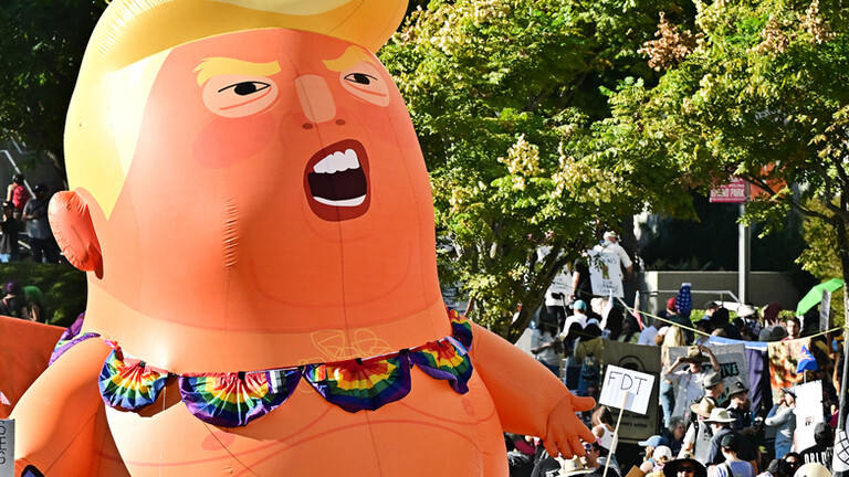 Eine No-Kings-Demonstration mit Plakaten und einer großen aufblasbaren Puppe in Form von Donald Trump