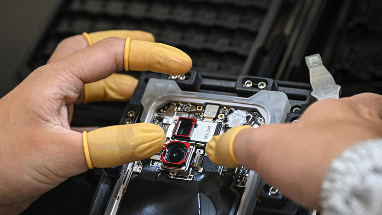 Mit Fingerlingen überzogene Finger stellen ein Smartphon zusammen im Werk des Herstellers Honor (22.10.2025, Shenzhen, China)