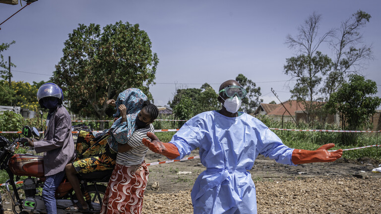Der medizinische Helfer Dieudonné Sezabo  bittet mit Gesten um Hilfe beim Transport eines Patienten mit Ebola-Verdacht