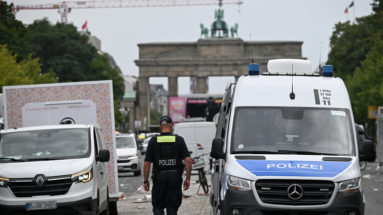 Polizist geht die Straße des 17. Juni in Richtung Brandenburger Tor entlang; rechts steht ein Polizeiauto (Berlin, 26.07.206)