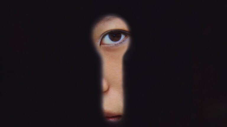 Eine chinesische Frau blickt in Schanghai durch ein Schlüsselloch