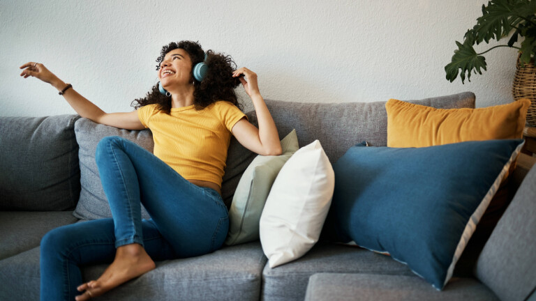 Eine Frau sitz auf dem Sofa und hört Musik.
