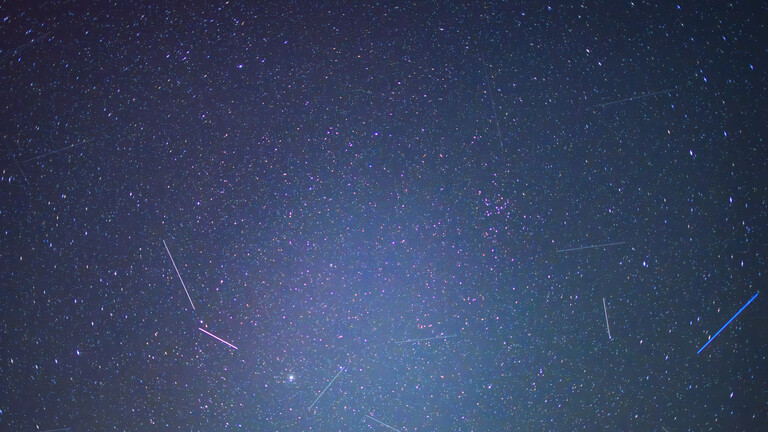 Satelliten und andere Objekte sind als Leuchtspuren zwischen den Sternen am Nachthimmel