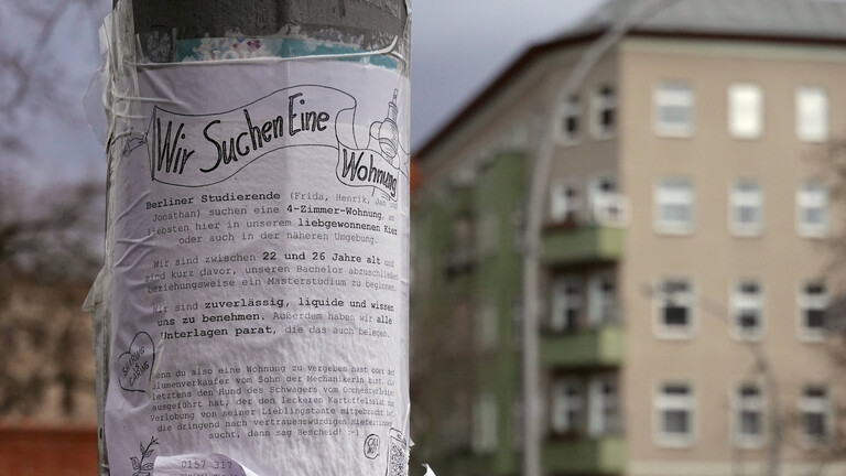 An einem Laternenpfahl hängt ein Zettel, es ist eine Suchanzeige von Studierenden für eine Wohnung.
