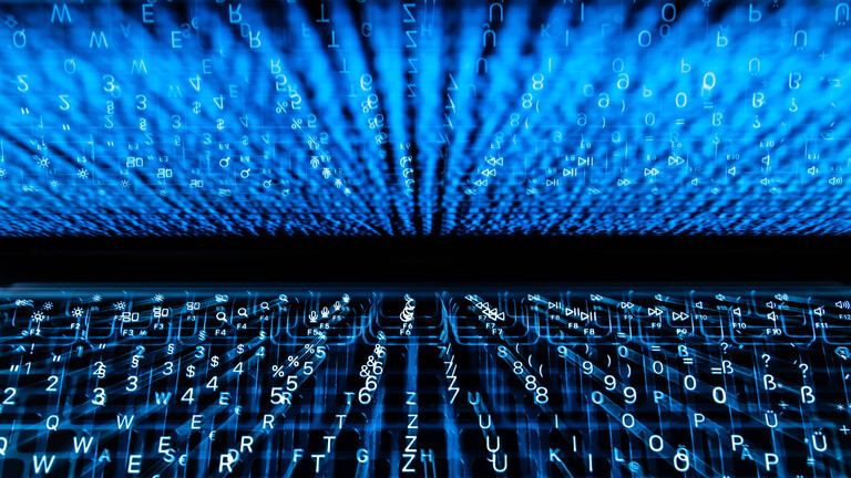 Die beleuchtete Tastatur eines Laptops spiegelt sich im Display wieder. (Aufnahme mit Zoomeffekt).