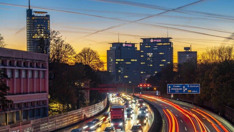 Abendlicher Verkehr, teils mit Stau, zäh fließendem Verkehr auf der Autobahn A40, Skyline von Essen, links RWE Turm, Mitte Evonik Konzern Zentrale, Essen, NRW, Deutschland Verkehr A40 Essen