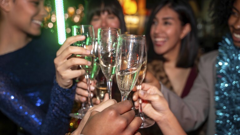 Vielfältige Gruppe von Freunden, die ein Ereignis feiern, auf einer modernen Party mit Champagnergläsern anstoßen und freudige Momente während eines festlichen Abends genießen