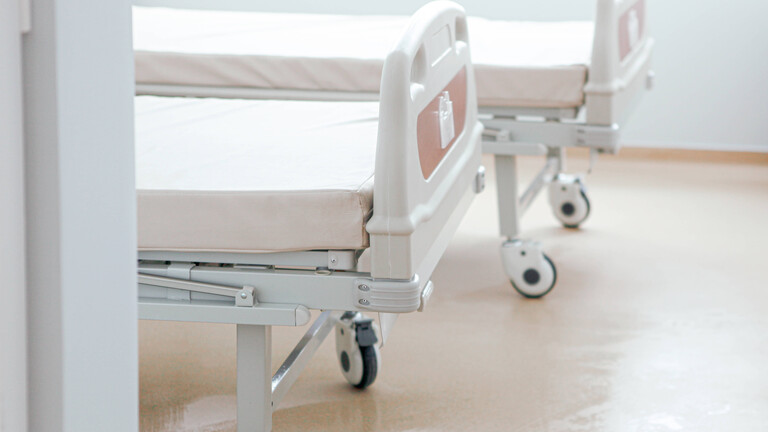 Zwei frisch bezogene, leere Krankenhausbetten mit Rollen.