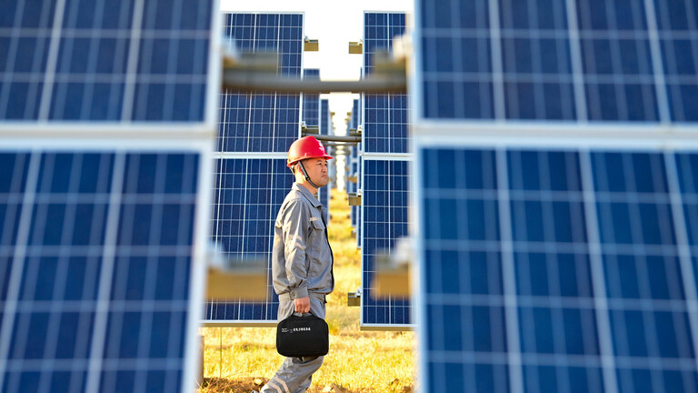 In Ulanhot in China läuft ein Arbeiter zwischen Solar-Panels hindurch.