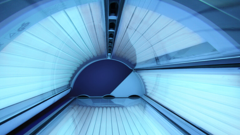 Blick in eine leere Solarium-Röhre, die strahlt in leicht bläulichem Licht.