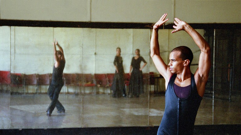 Ein Balletttänzer trainiert vor einem Wandspiegel.