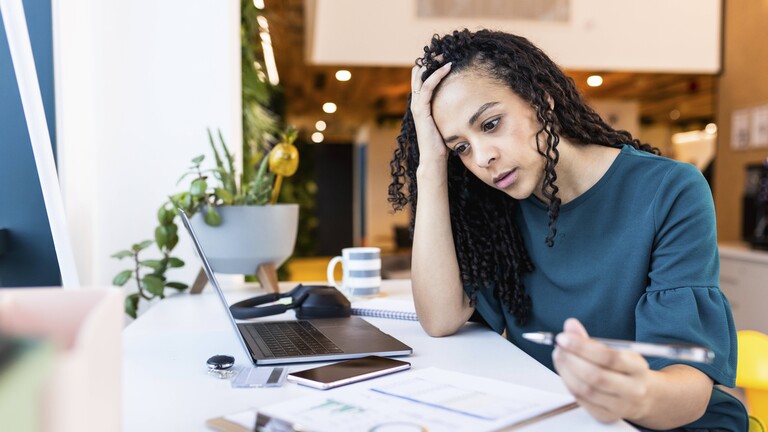 Eine Frau sitzt gestresst vor einem Laptop