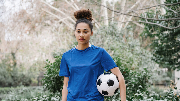 Frau in einem park in Barcelona, mit einem Fußball unter dem Arm.