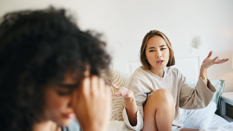Zwei Frauen diskutieren. Die eine stützt die Stirn in die Hand.