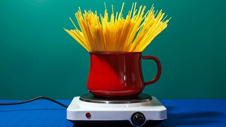 Auf einer Herdplatte steht ein Topf. Darin sind viele Spaghetti.
