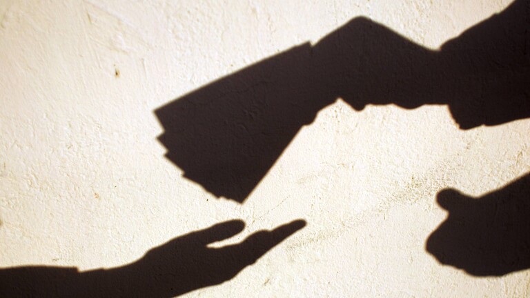 Schatten auf einer Wand zeigen Hände gegenüber voneinander. Die eine Hand legt Geldscheine in die andere gegenüber.