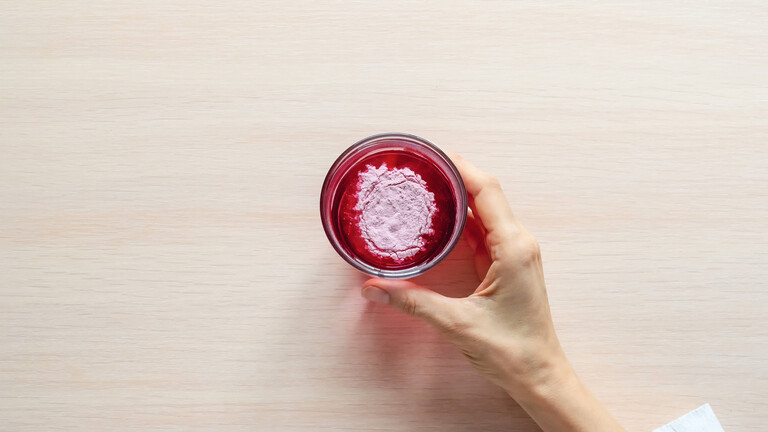 Ein Glas natürliches Beeren-Kollagen-Proteinpulver in einem Glas Wasser
