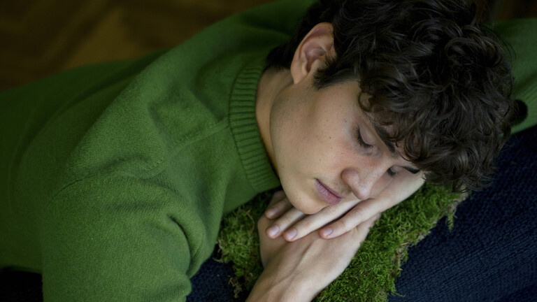 Ein junger Mann liegt auf dem Sofa und macht einen Mittagsschlaf