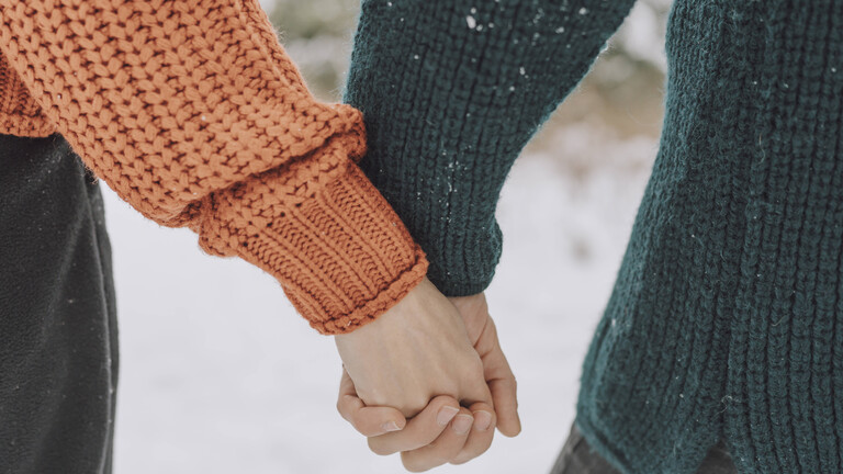 Naheaufnahme der Hände zweier junger Frauen, die Händchenhalten