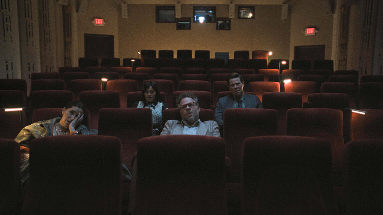 Vier Personen sitzen in einem Kinosaal. Es ist dunkel. Eine von ihnen, ein bärtiger Mann mit Brille, guckt entsetzt. Eine Frau zu seiner Rechten schlägt eine Hand vor das Gesicht. Was sie sehen, entspricht offenbar nicht ihren Erwartungen.