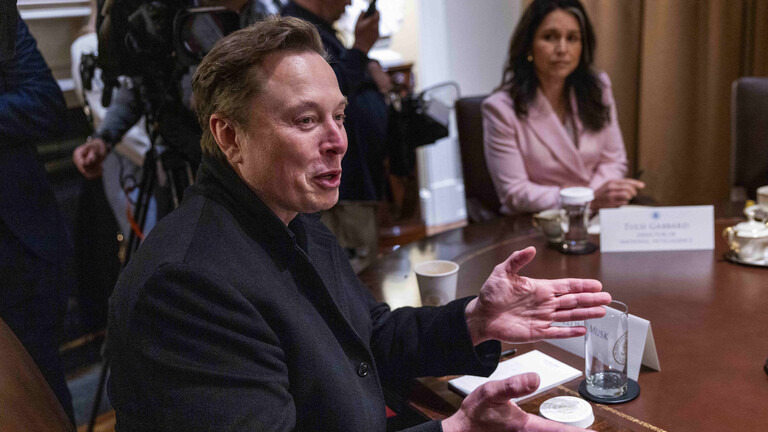 Elon Musk, Chef von Tesla, sitzt bei einer Kabinettssitzung im Weißen Haus an einem Tisch, er lacht und gestikuliert mit den Händen.