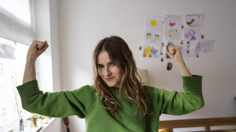 Frau zeigt Muskeln und lächelt