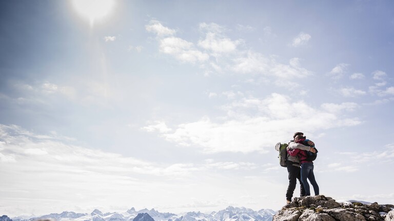 Ein Paar umarmt sich auf einem Berggipfel in Bayern.