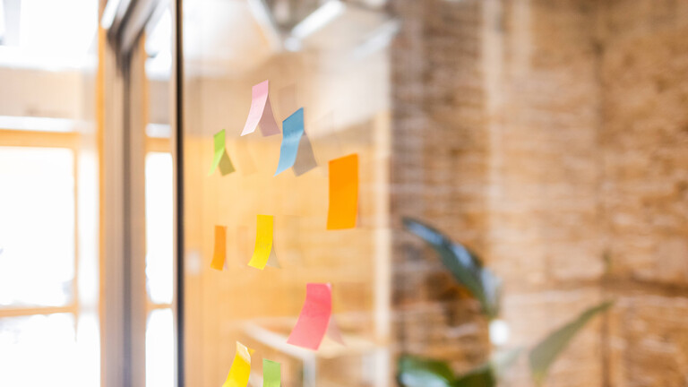Bunte Notizzettel auf einer Glaswand im Büro