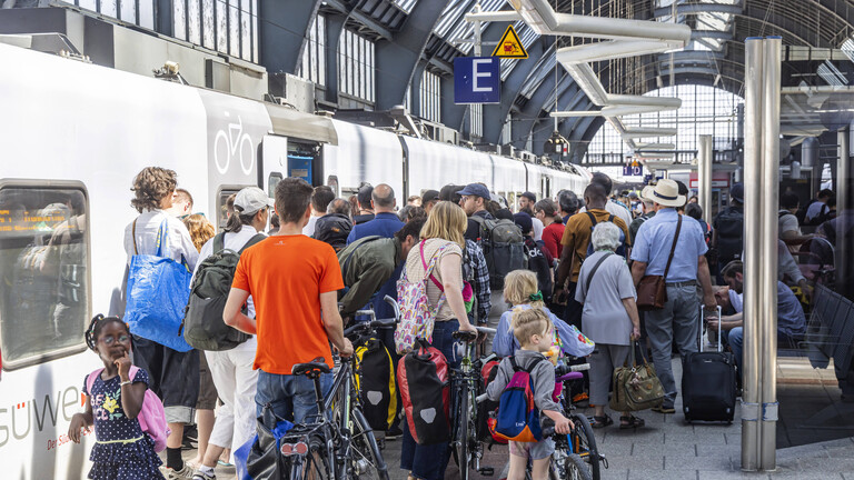 Menschenmasse versucht mit Gepäck und Rädern in einen Zug zu kommen (Bahnsteig im Hauptbahnhof Karlsruhe, 12.6.2025)