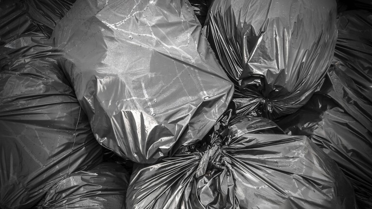 Schwarze volle Müllsäcke liegen übereinander.