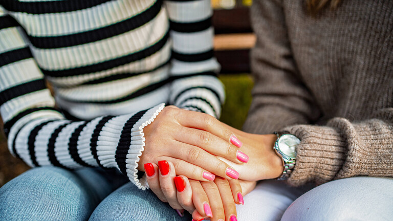 Freundinnen mit Nagellack halten einander die Hände