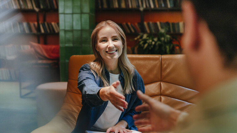 Frau gibt jungem Mann nach Bewerbungsggespräch die Hand