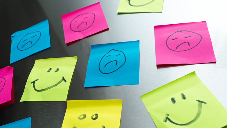 Bunte Haftnotizzettel mit lächelnden und traurigen Smileys.