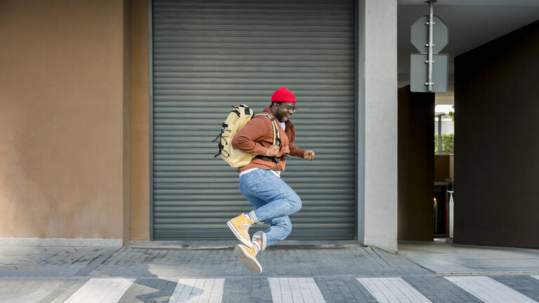 Ein Mann auf der Straße springt in die Luft und lacht.