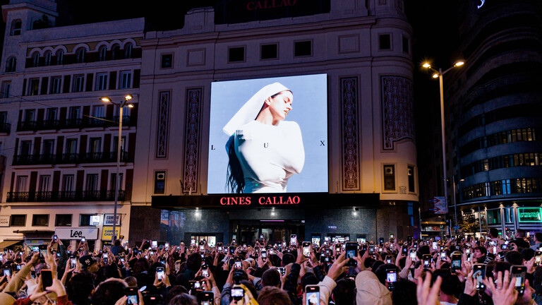 Dutzende Menschen betrachten am 20. Oktober 2025 auf der Plaza de Callao in Madrid, Spanien, das Cover von Rosalias neuem Album „Lux“