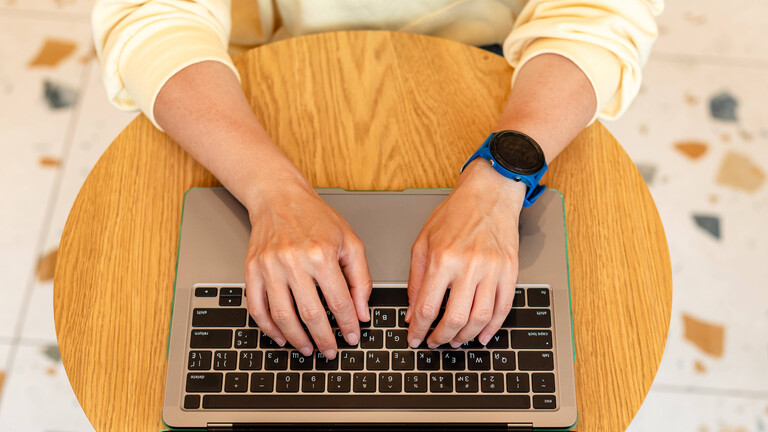 Nahaufnahme von Frauenhänden, die auf die Tastatur eines Laptops tippen.