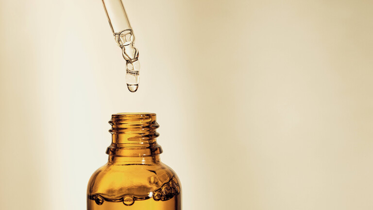 Tropfer, der Serum in eine braune Flasche abfüllt