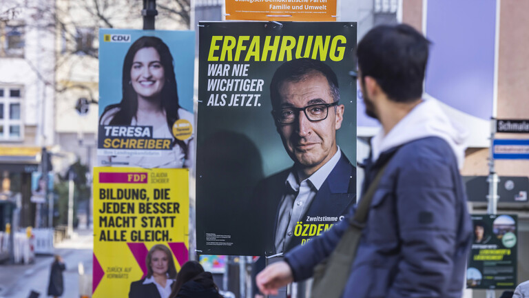 Mann schaut auf ein Wahlplakat von Özdemir (Grüne)