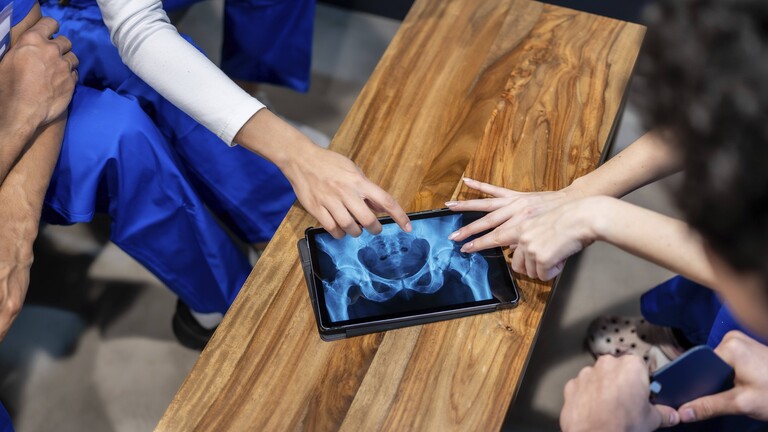 Gesundheitsfachkräfte analysieren ein Hüft- und Beckenröntgenbild auf einem Tablet
