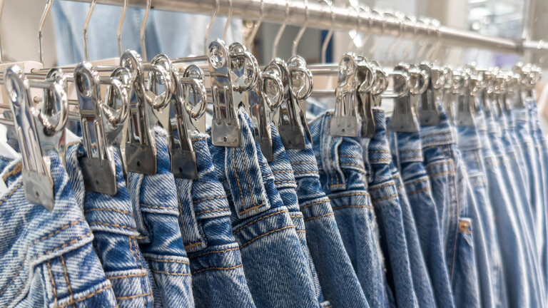 Blaue Denim Jeans hängend auf Einzelhandelsregal mit Metallclips