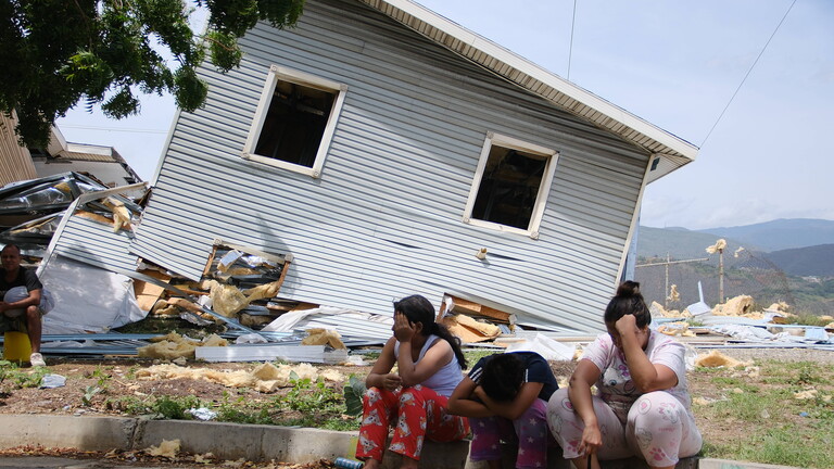 Ein Blick auf ein zerstörtes Haus nach dem Erdbeben in Caracas, Venezuela, am 25. Juni 2026. Drei Frauen sitzen erschöpft und traurig vor dem Haus.