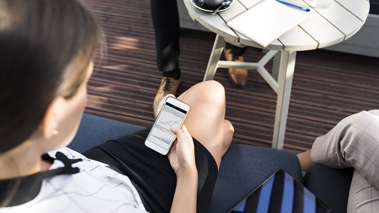 Eine Frau checkt Kurse auf ihrem Handy.